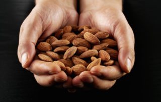 person holding out both hands full of almonds