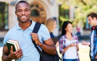 student athlete holding books on campus with students in the background