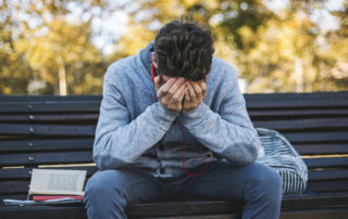 Teenager sits on a bench in the park and listen to music and learning for exame