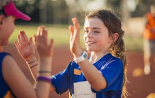 Two girls are high fiving after a difficult race in athletics club.