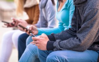 Group of teenagers sitting outdoors using their mobile phones