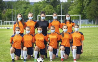 Female soccer team wearing face masks during coronavirus pandemic.