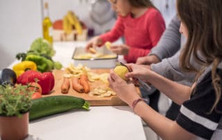 Close-up photo of two little girls cooking in the kitchen together with their father