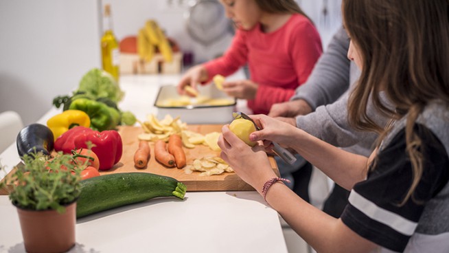 Close-up photo of two little girls cooking in the kitchen together with their father