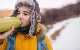 Boy drinking water while hiking on snowcapped mountain