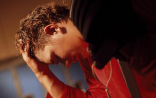 Athlete in dressing room with hand on head about to throw up