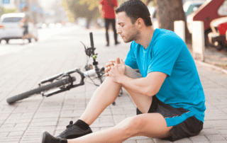 man holding injured knee with a potential acl injury while riding bike