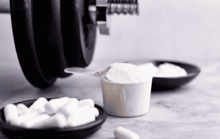 glutamine workout supplement powder and pill form next to a barbell