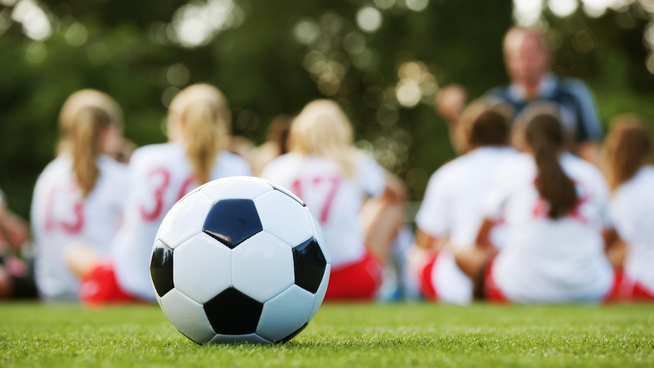 coach giving speech to girls soccer team at halftime