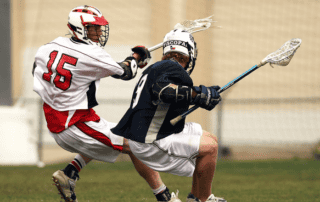 male lacrosse athletes playing in a game