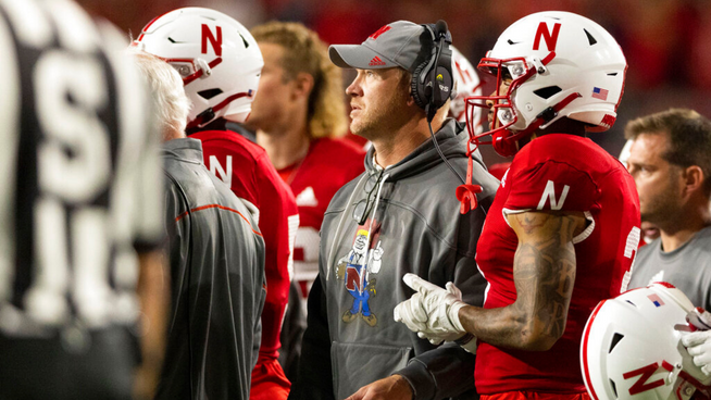 former nebraska college football head coach with team on sideline