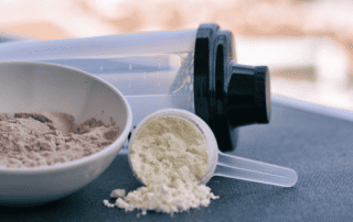 whey protein powder with shaker and scooper on table