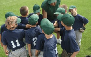 youth sports male baseball team in huddle with coach